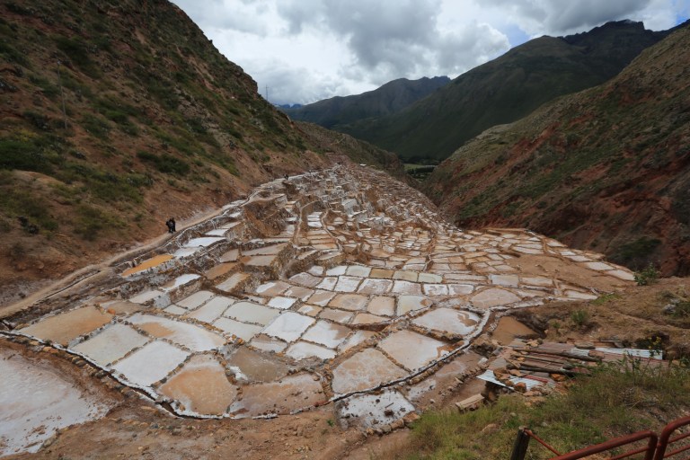 Salt water flows out of the mountain into a system of canals that are fed to pools where the water is evaporated.  First used by the Incas.